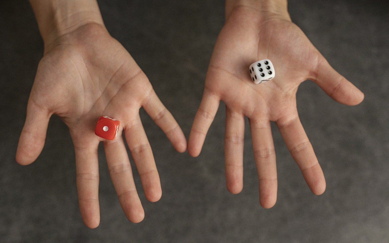 Open palms each holding a single die, one red showing one and one white showing six