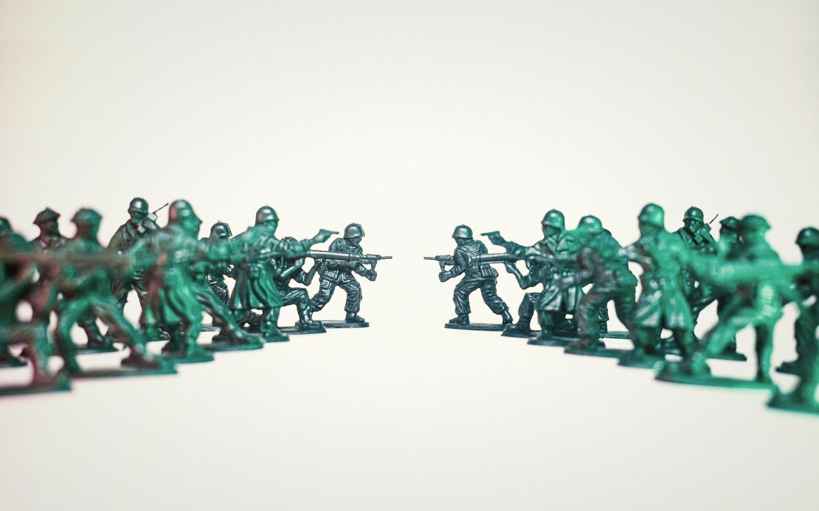 Two rows of green plastic toy soldiers facing off in mock combat formation