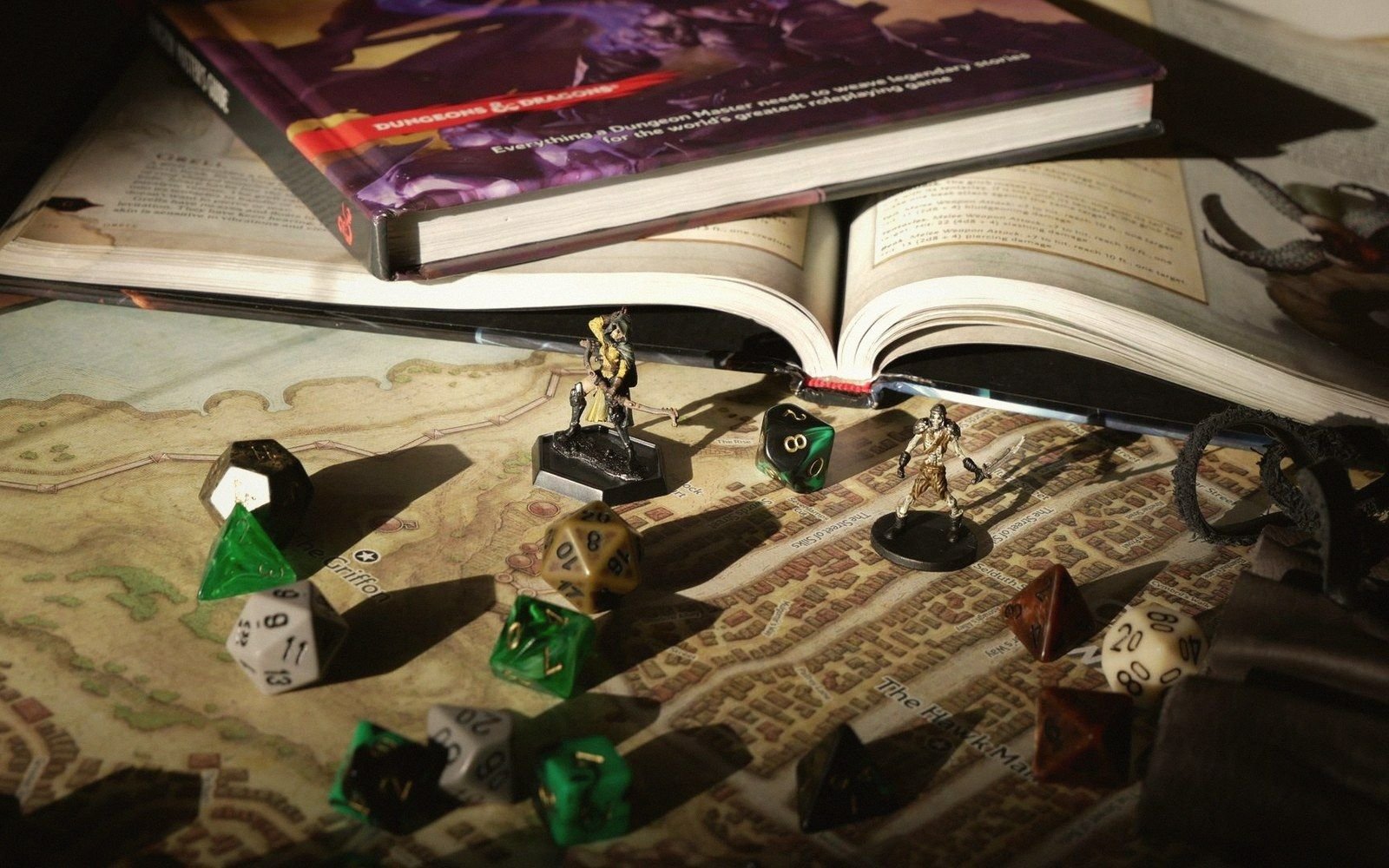 Polyhedral dice and miniature figures arranged on a fantasy map beside open rulebooks