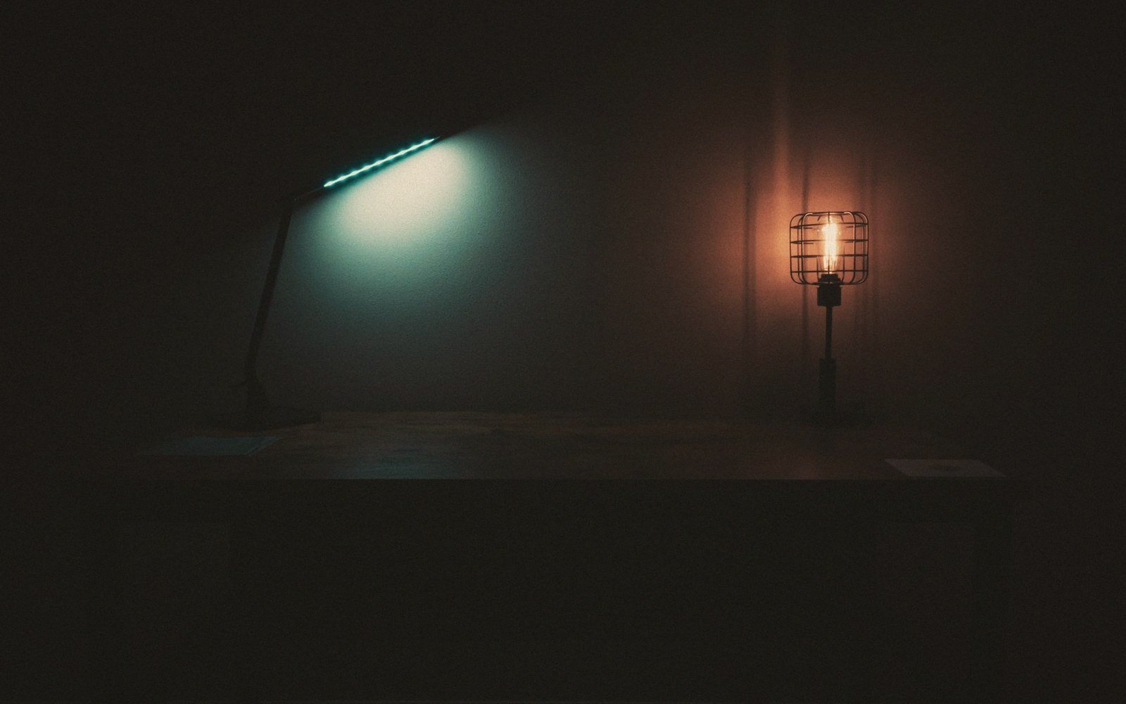 A warm desk lamp and a cold mug at the table edge